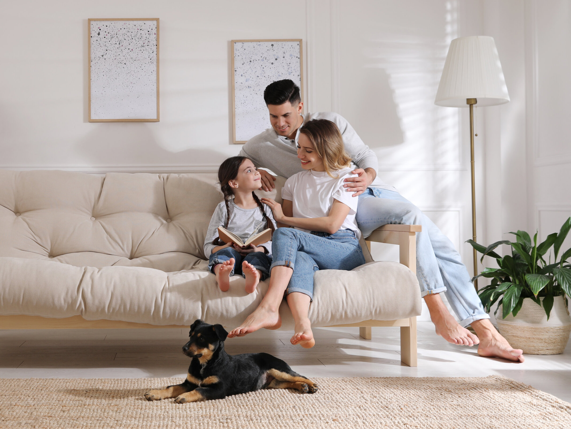 AdobeStock_433610564 Happy family on sofa and puppy in living room