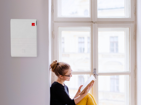 A young happy college female student with a book sitting on window sill at home, studying.
