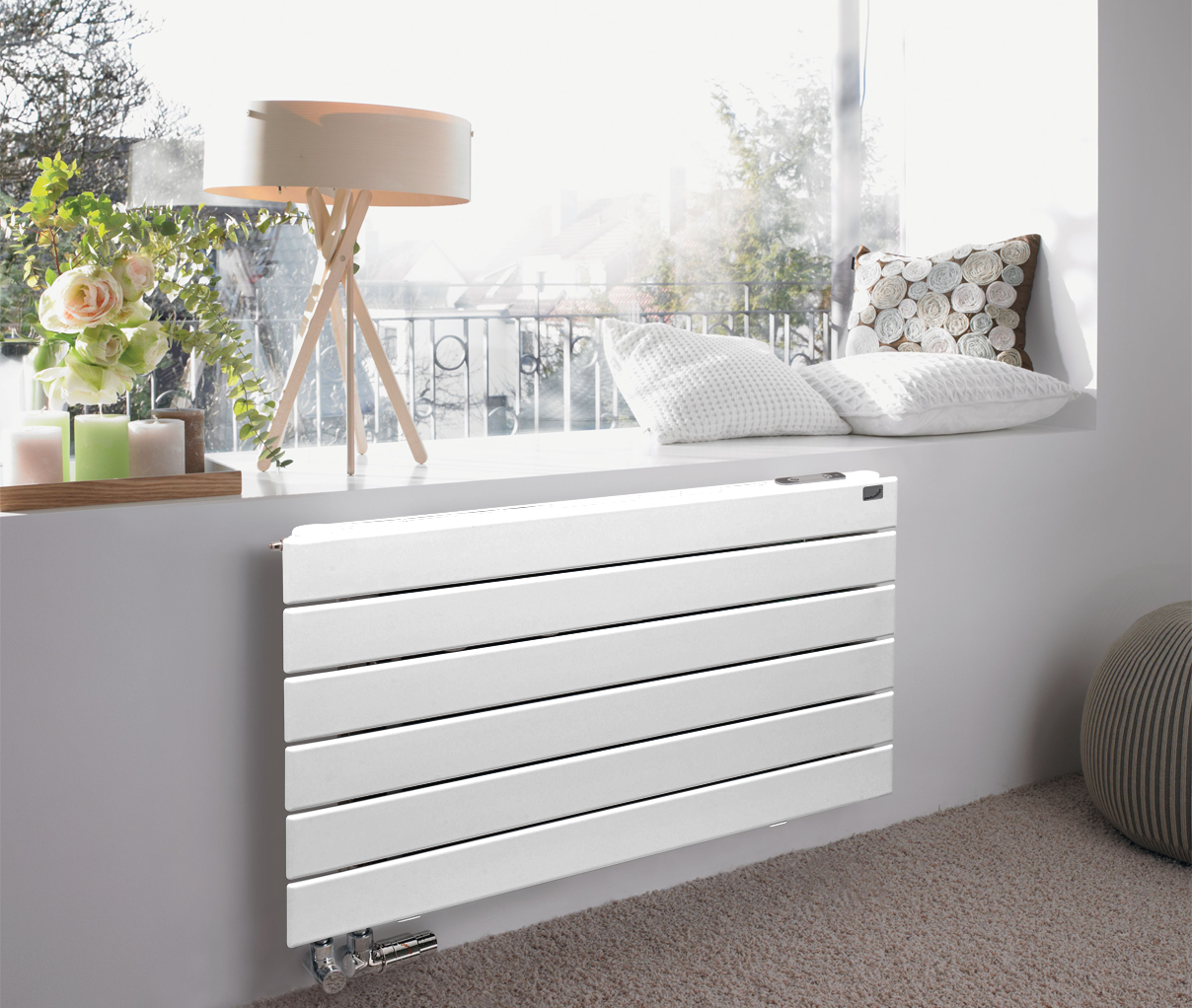 Radiatore di design bianco installato sotto una finestra soleggiata in un soggiorno moderno
